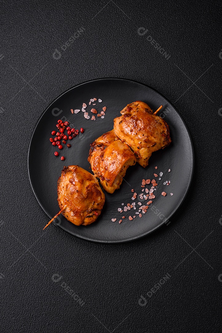 Delicioso kebab de frango fresco com sal, especiarias e ervas sobre um fundo escuro de concreto