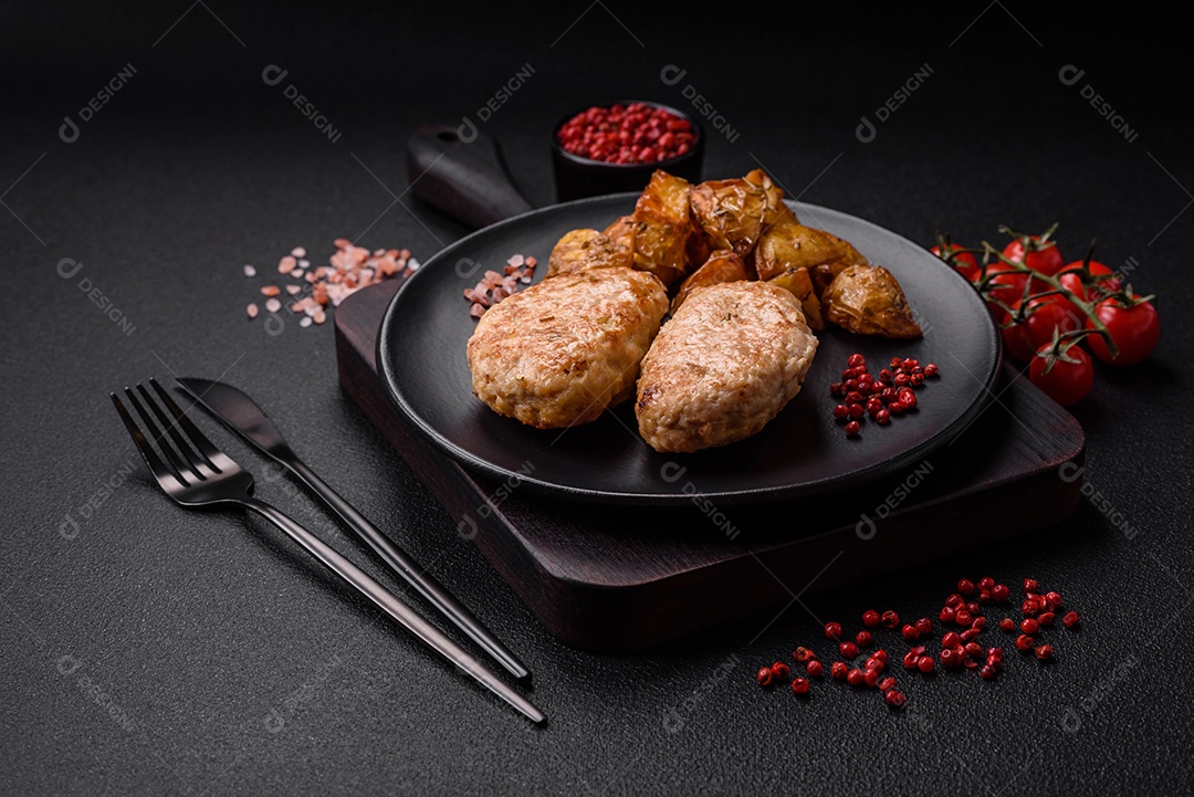 Deliciosas costeletas de frango fresco ou almôndegas com sal, especiarias e ervas sobre um fundo escuro de concreto