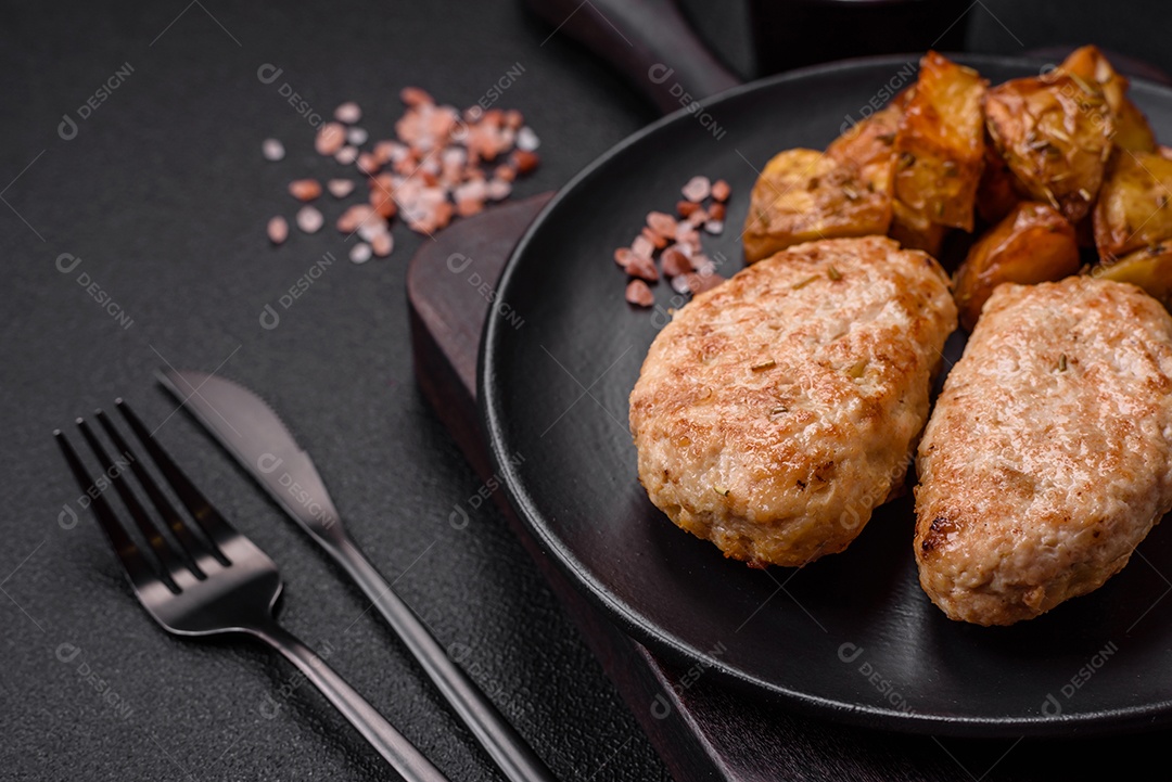 Deliciosas costeletas de frango fresco ou almôndegas com sal, especiarias e ervas sobre um fundo escuro de concreto