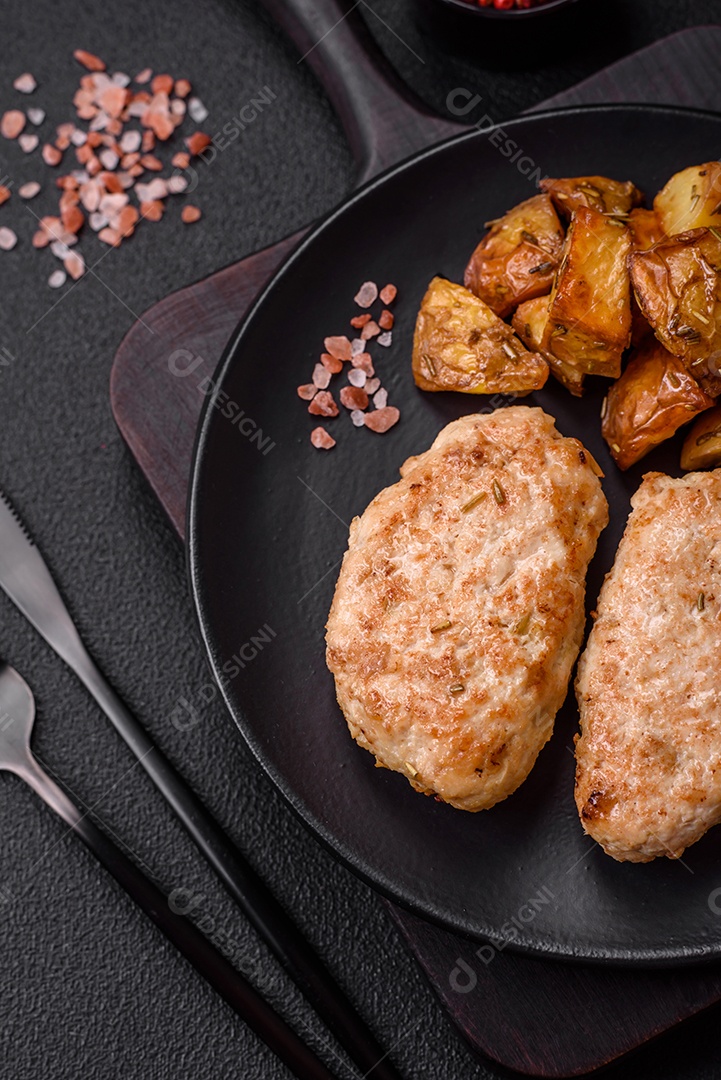 Deliciosas costeletas de frango fresco ou almôndegas com sal, especiarias e ervas sobre um fundo escuro de concreto