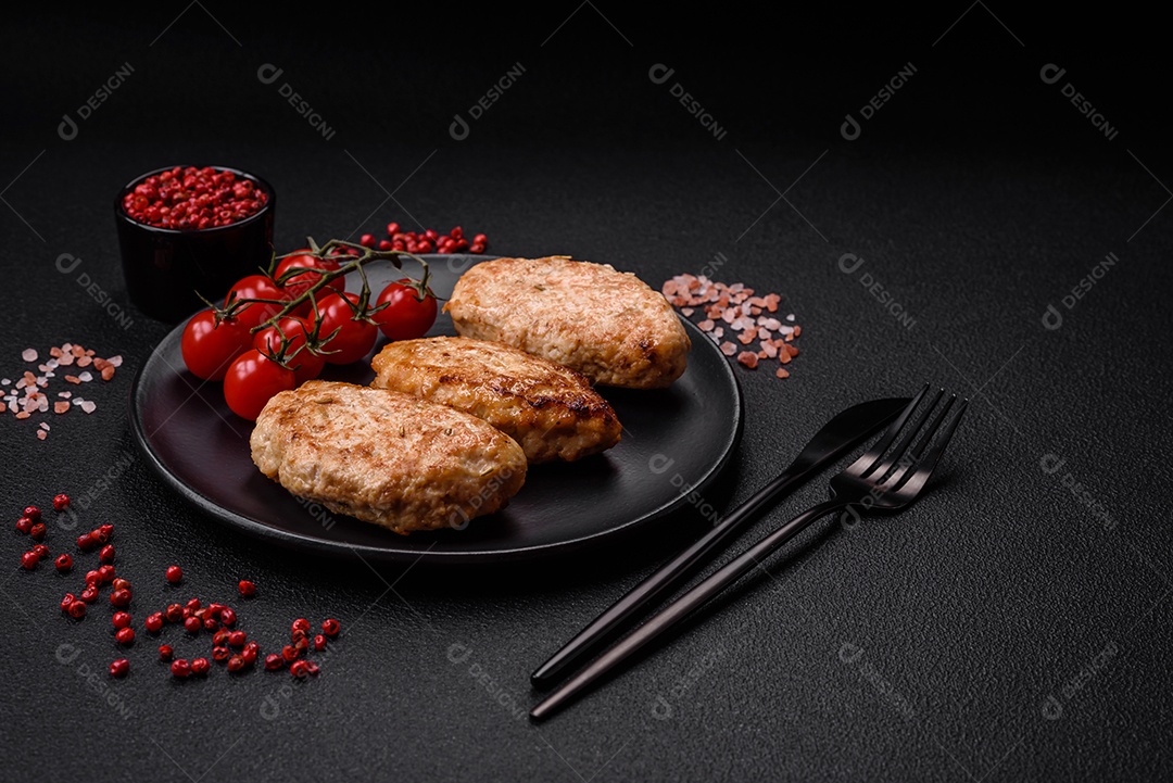 Deliciosas costeletas de frango fresco ou almôndegas com sal, especiarias e ervas sobre um fundo escuro de concreto