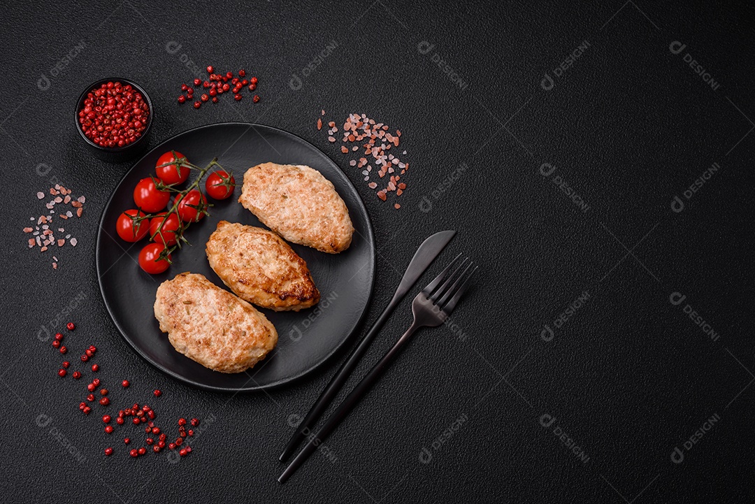 Deliciosas costeletas de frango fresco ou almôndegas com sal, especiarias e ervas sobre um fundo escuro de concreto