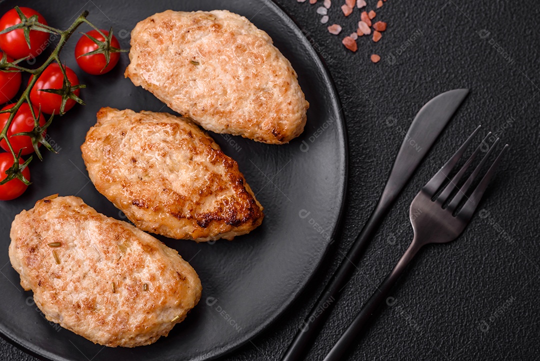 Deliciosas costeletas de frango fresco ou almôndegas com sal, especiarias e ervas sobre um fundo escuro de concreto
