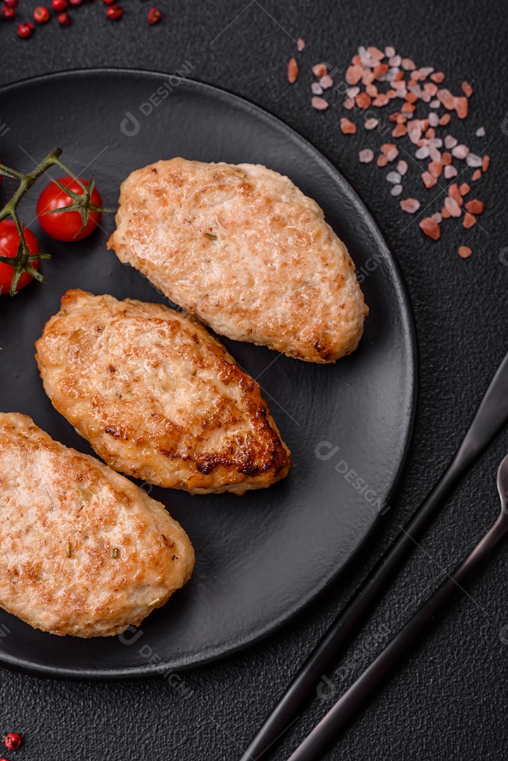 Deliciosas costeletas de frango fresco ou almôndegas com sal, especiarias e ervas sobre um fundo escuro de concreto