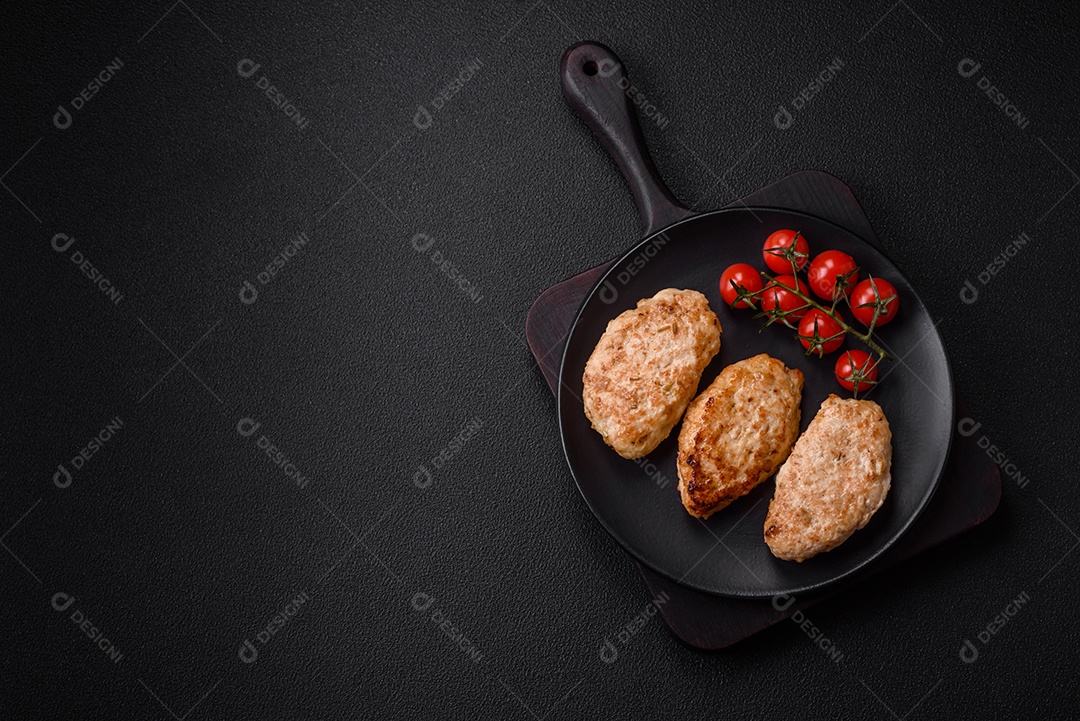 Deliciosas costeletas de frango fresco ou almôndegas com sal, especiarias e ervas sobre um fundo escuro de concreto