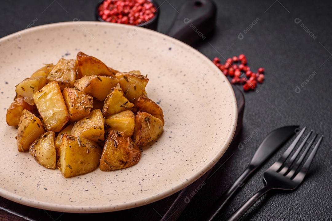 Deliciosas fatias de batata frita crocante com sal, especiarias e ervas sobre um fundo escuro de concreto