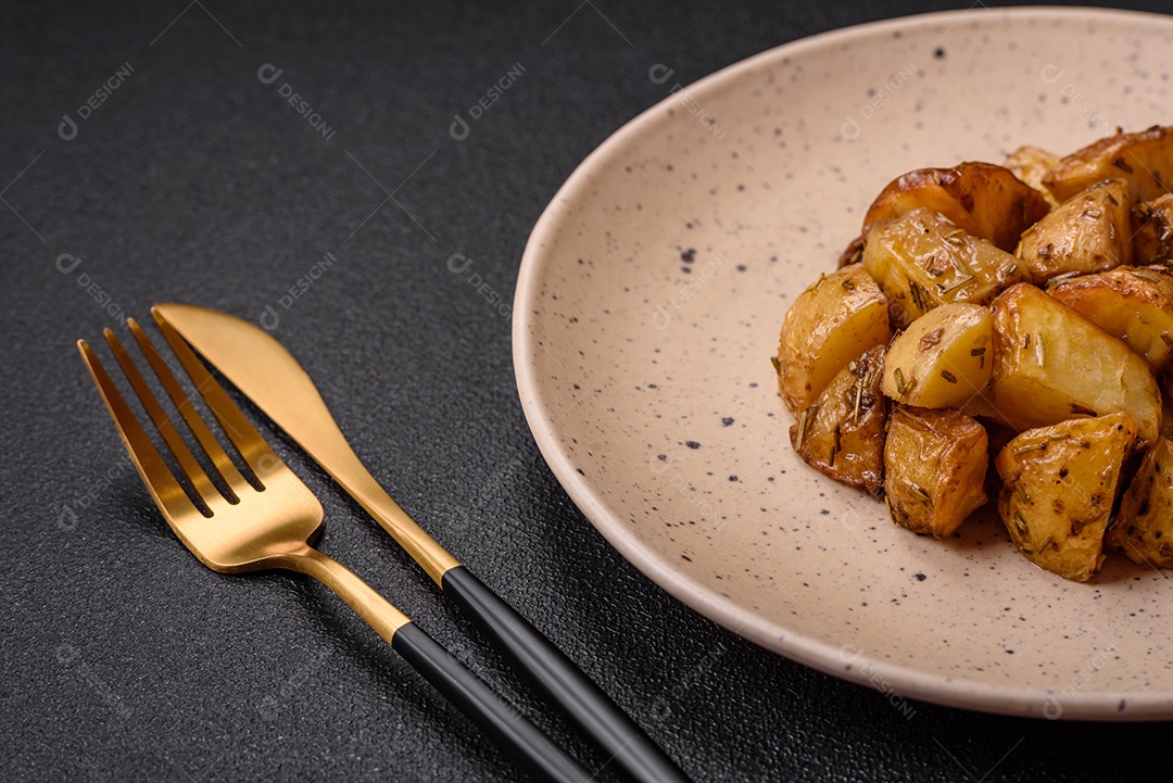 Deliciosas fatias de batata frita crocante com sal, especiarias e ervas sobre um fundo escuro de concreto