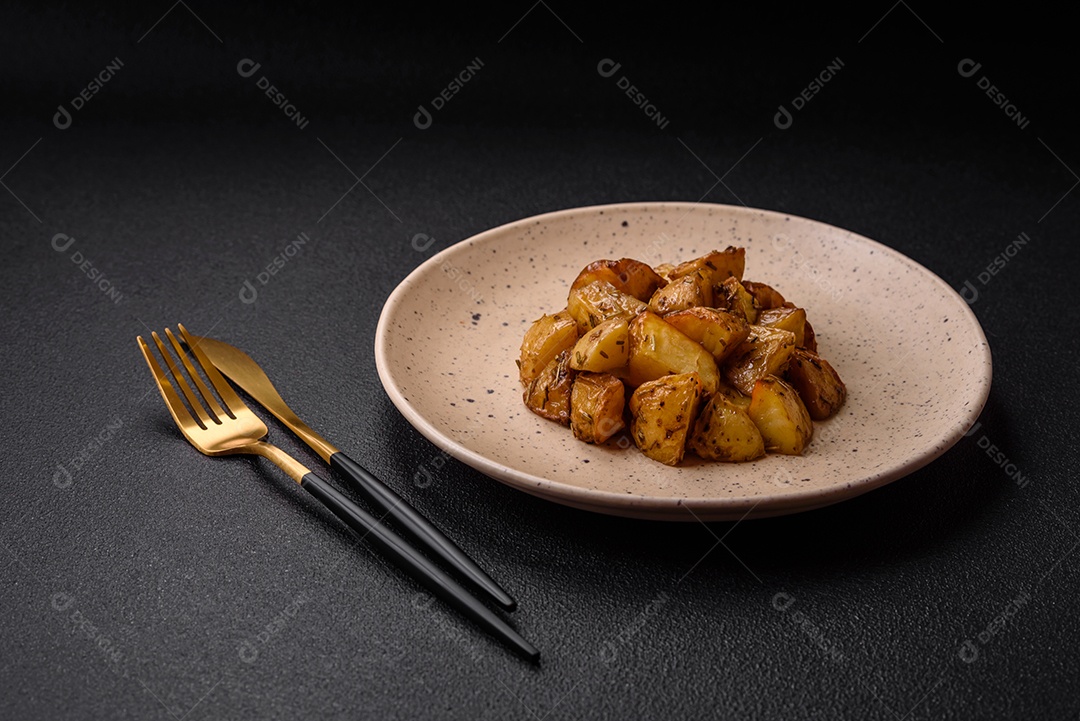 Deliciosas fatias de batata frita crocante com sal, especiarias e ervas sobre um fundo escuro de concreto