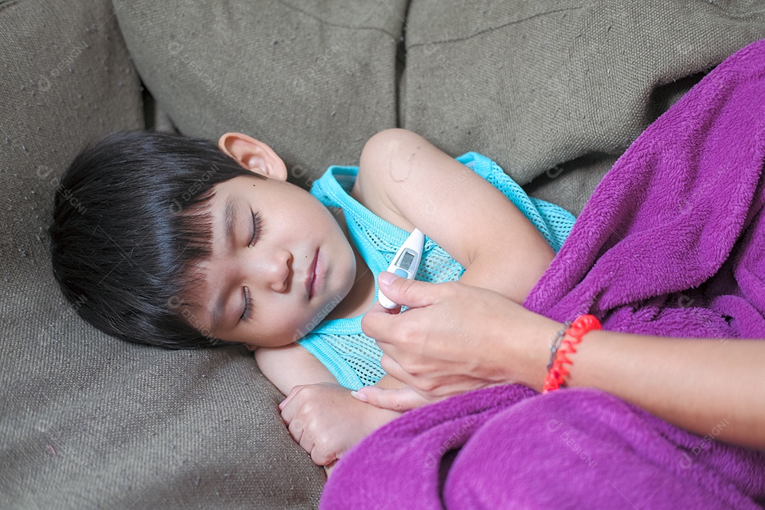 Pequeno menino asiático deitado doente medindo febre