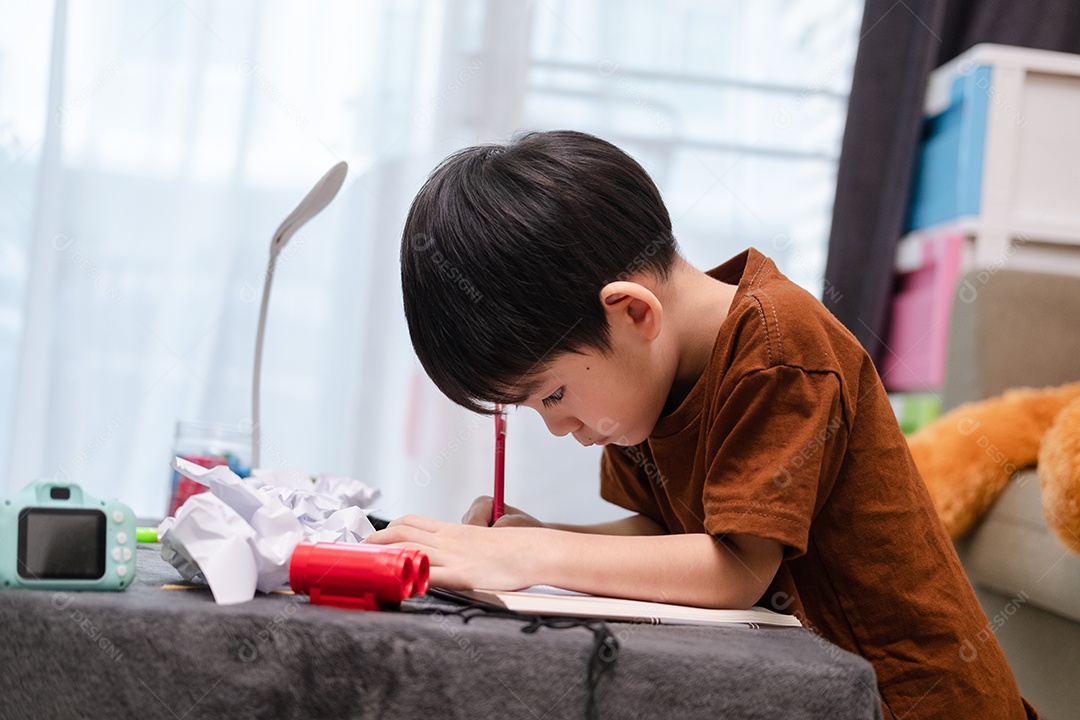 Menino asiático desenhando na mesa