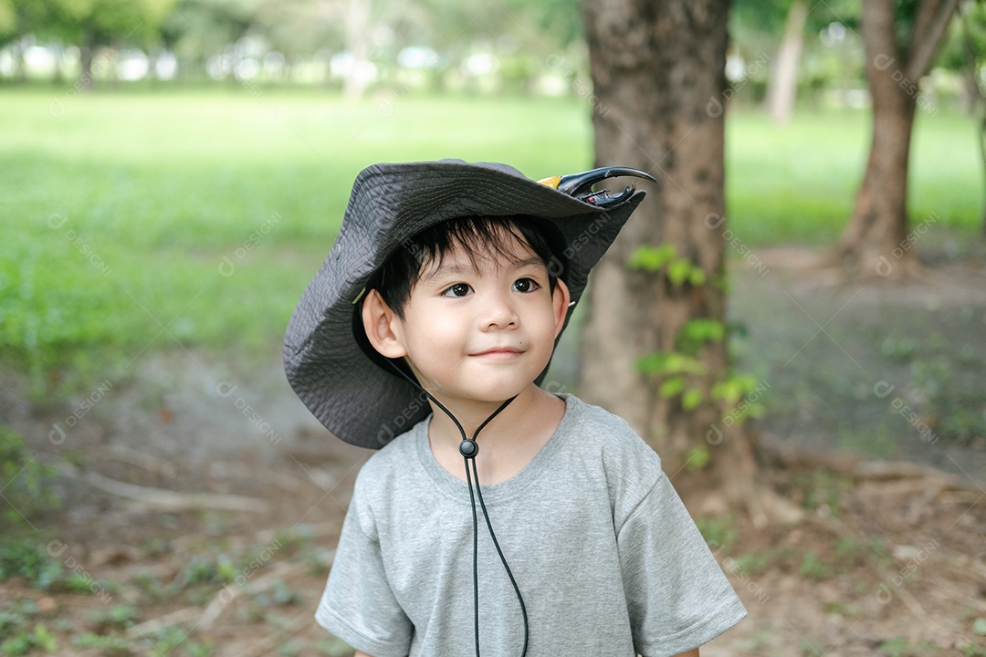 Menino asiático sorridente usando um chapéu em um traje de exploração da selva