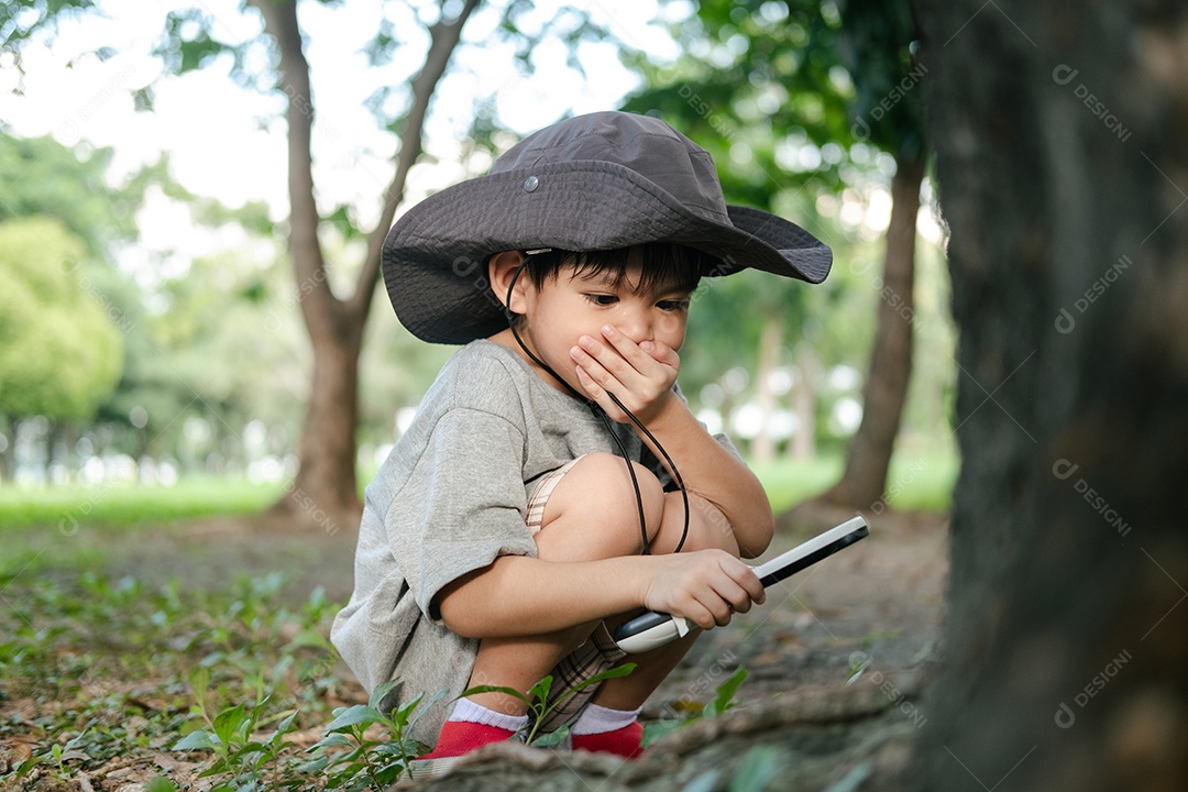 Menino asiático usando um chapéu em um traje de exploração florestal
