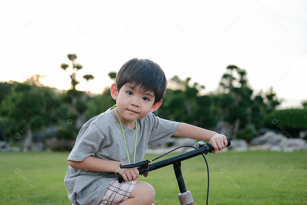 Menino asiático brincando de bicicleta no parque