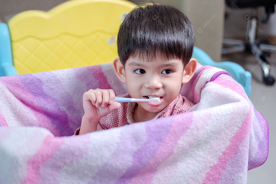 Um menino escova os dentes em sua amada caixa de brinquedos