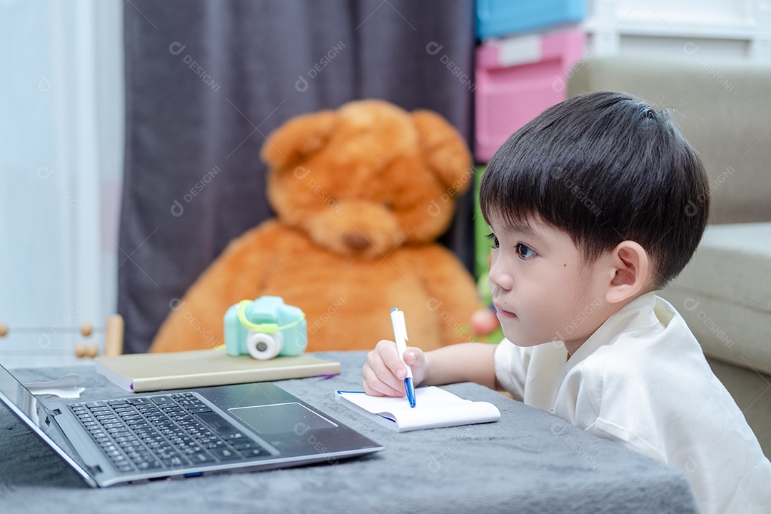 Menino asiático estudando ou assistindo no laptop