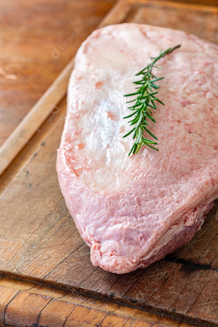 Picanha crua ou lombo com alecrim sobre mesa de madeira