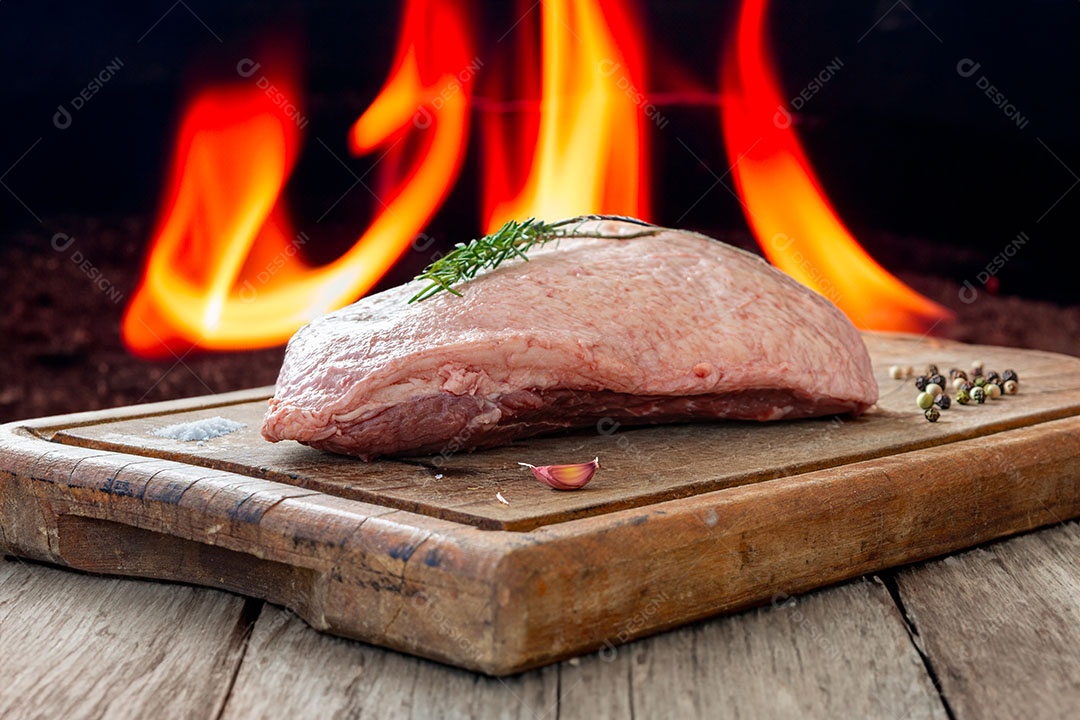 Picanha crua ou lombo de cima em uma tábua com fundo de fogo