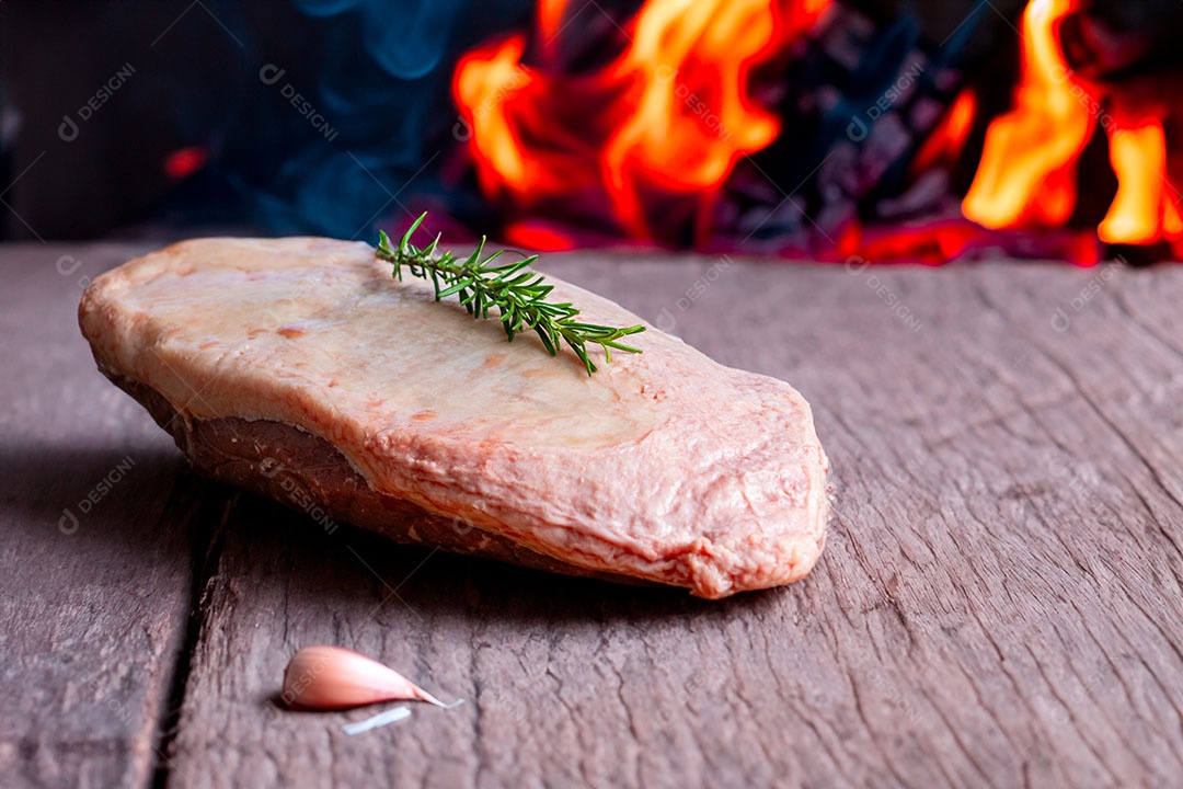 Picanha crua ou lombo de cima em uma tábua com fundo de fogo