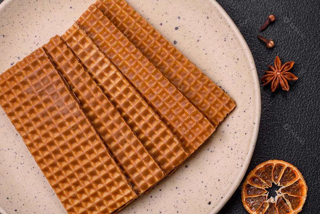 Deliciosos waffles retangulares crocantes e doces em uma placa de cerâmica sobre um fundo escuro de concreto