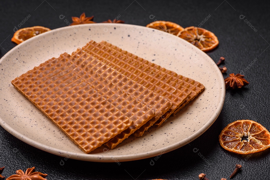 Deliciosos waffles retangulares crocantes e doces em uma placa de cerâmica sobre um fundo escuro de concreto