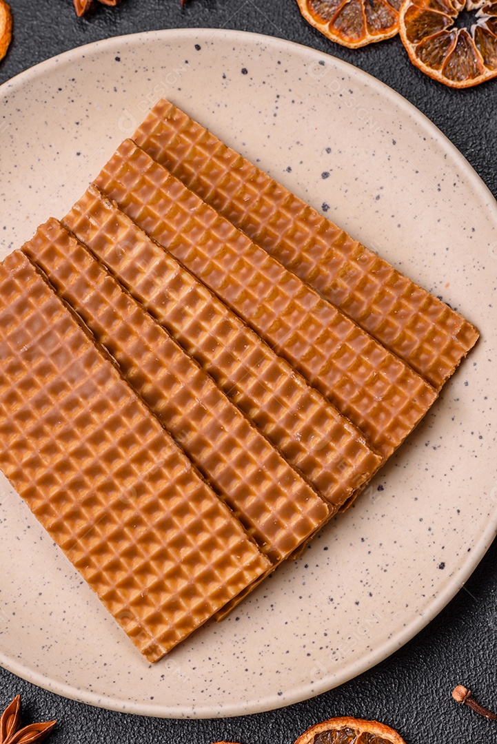 Deliciosos waffles retangulares crocantes e doces em uma placa de cerâmica sobre um fundo escuro de concreto