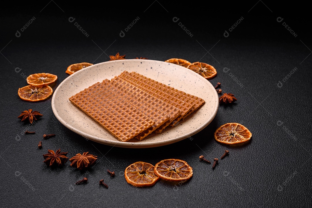 Deliciosos waffles retangulares crocantes e doces em uma placa de cerâmica sobre um fundo escuro de concreto