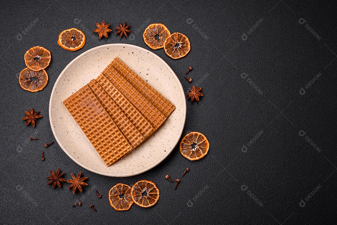 Deliciosos waffles retangulares crocantes e doces em uma placa de cerâmica sobre um fundo escuro de concreto