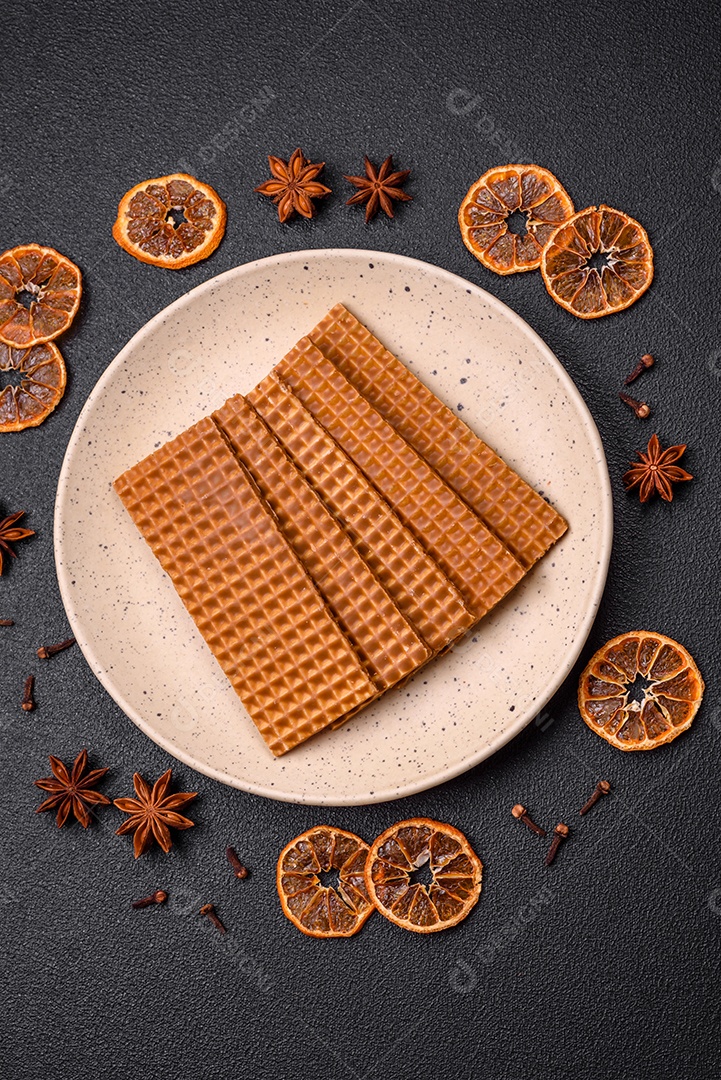 Deliciosos waffles retangulares crocantes e doces em uma placa de cerâmica sobre um fundo escuro de concreto