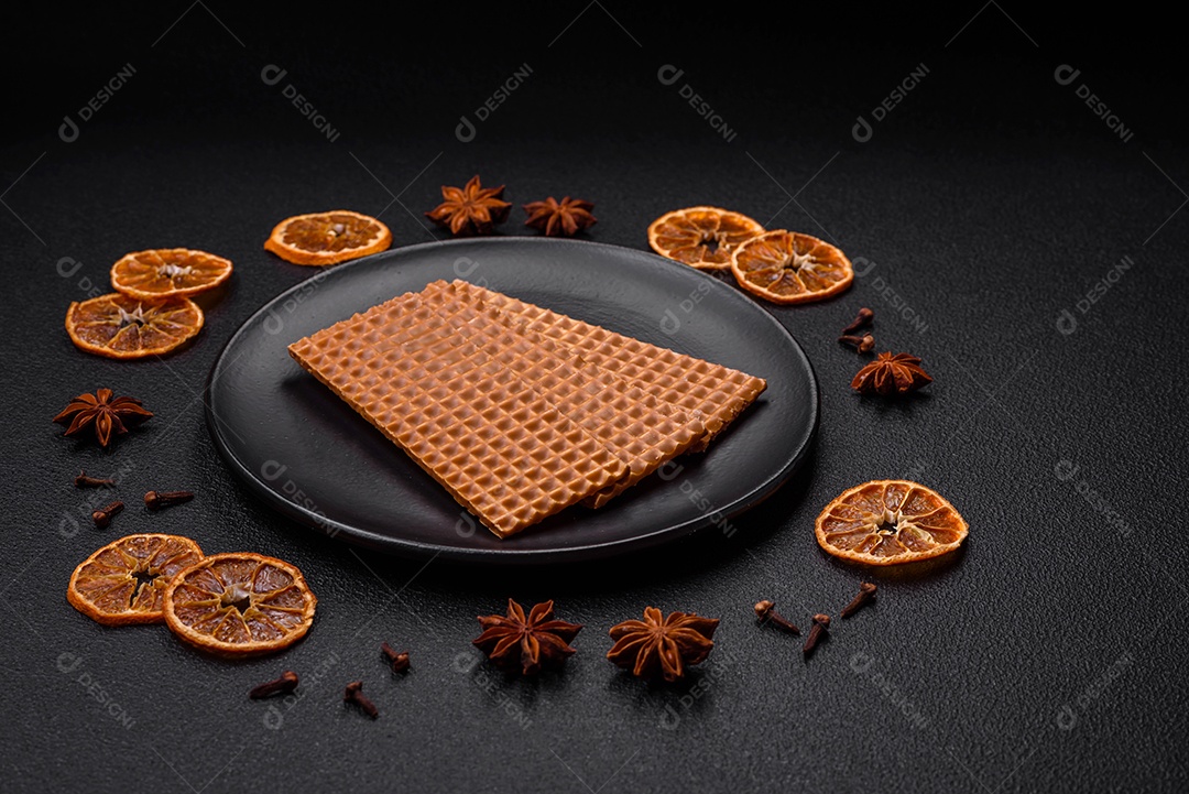 Deliciosos waffles retangulares crocantes e doces em uma placa de cerâmica sobre um fundo escuro de concreto