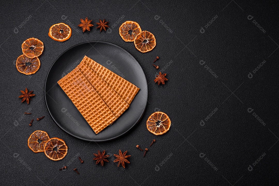 Deliciosos waffles retangulares crocantes e doces em uma placa de cerâmica sobre um fundo escuro de concreto