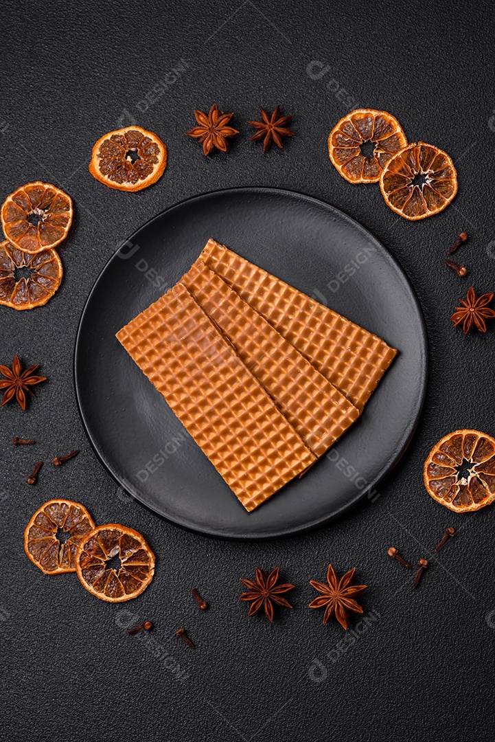 Deliciosos waffles retangulares crocantes e doces em uma placa de cerâmica sobre um fundo escuro de concreto