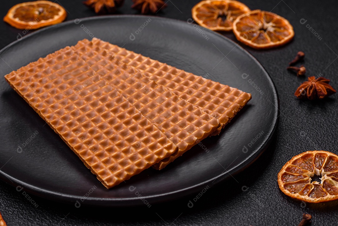 Deliciosos waffles retangulares crocantes e doces em uma placa de cerâmica sobre um fundo escuro de concreto