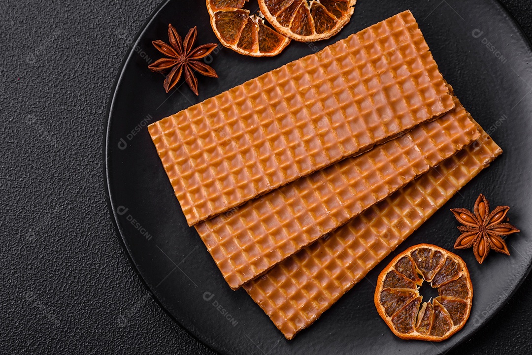 Deliciosos waffles retangulares crocantes e doces em uma placa de cerâmica sobre um fundo escuro de concreto