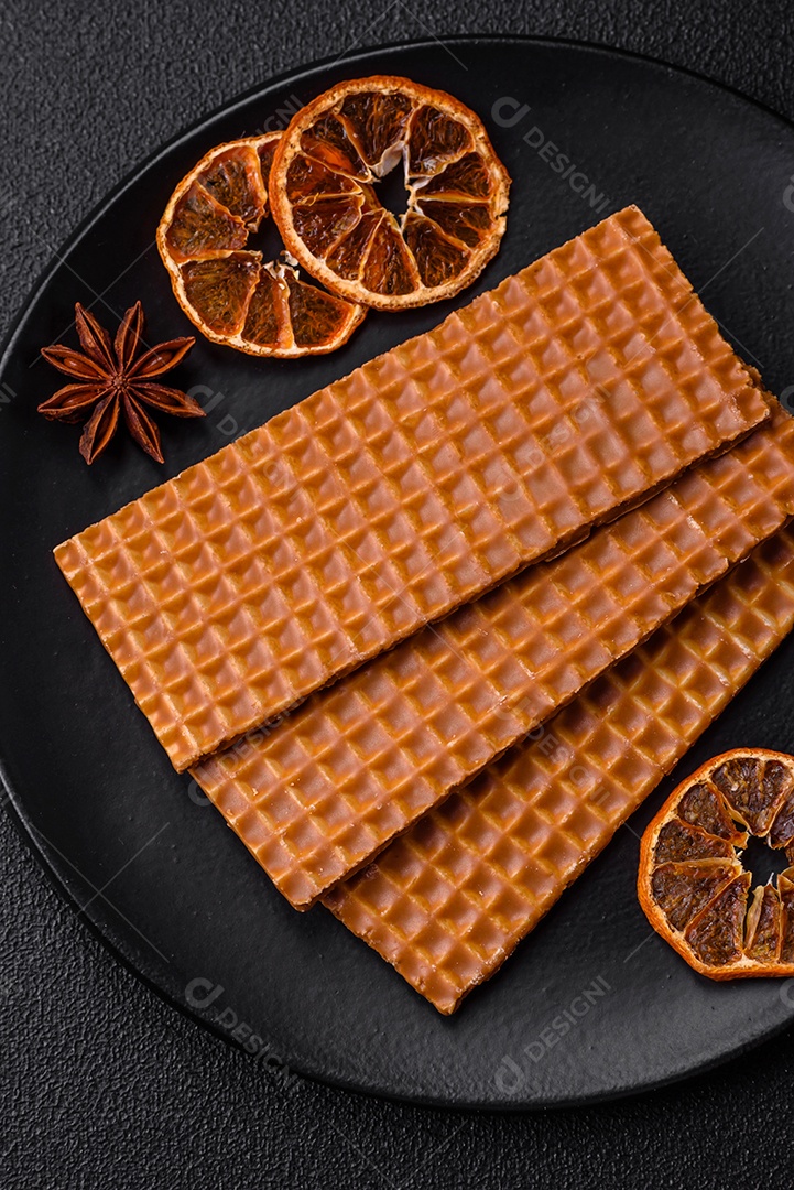 Deliciosos waffles retangulares crocantes e doces em uma placa de cerâmica sobre um fundo escuro de concreto