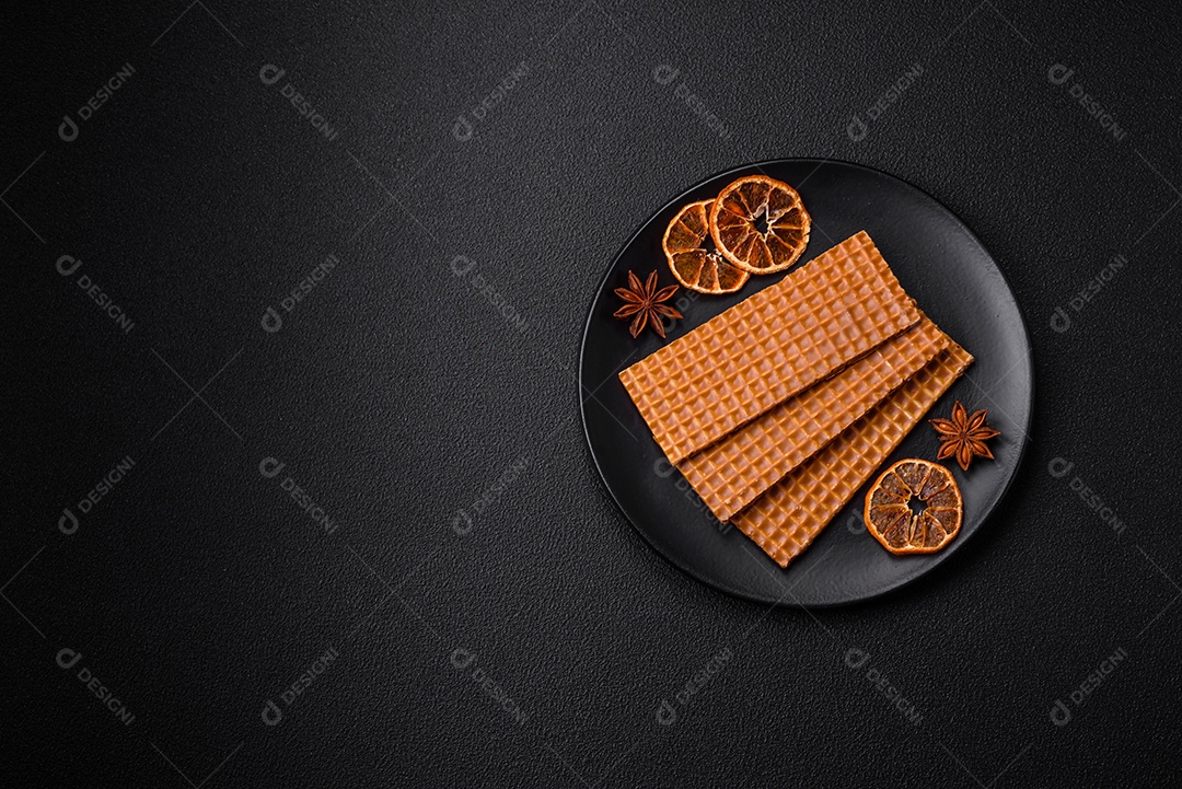 Deliciosos waffles retangulares crocantes e doces em uma placa de cerâmica sobre um fundo escuro de concreto