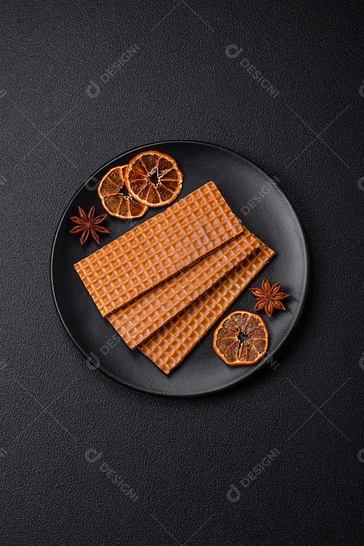 Deliciosos waffles retangulares crocantes e doces em uma placa de cerâmica sobre um fundo escuro de concreto