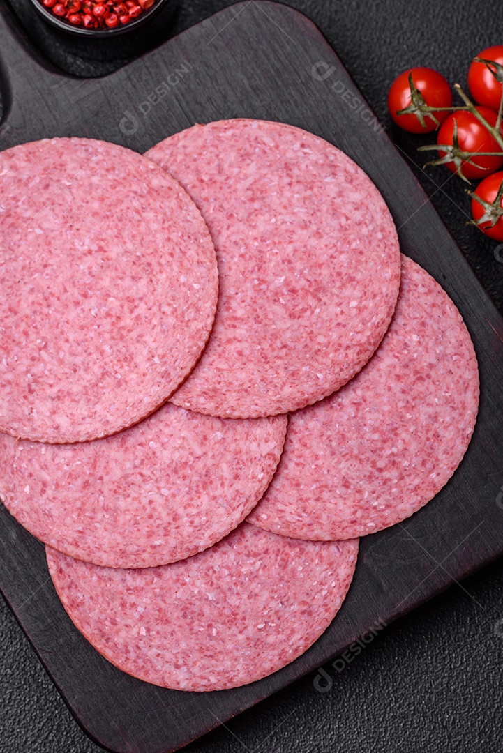 Deliciosa salsicha de salame fumado com sal, especiarias e ervas cortadas em fatias sobre um fundo escuro de concreto