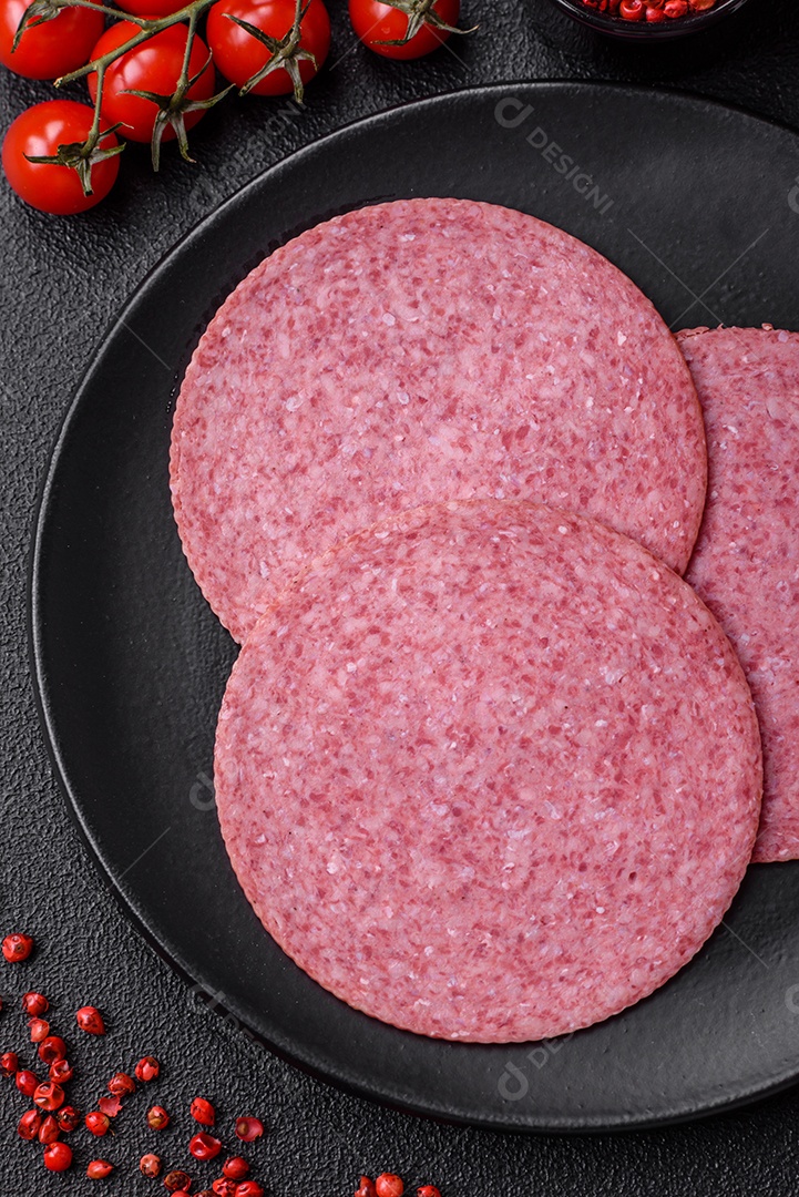 Deliciosa salsicha de salame fumado com sal, especiarias e ervas cortadas em fatias sobre um fundo escuro de concreto