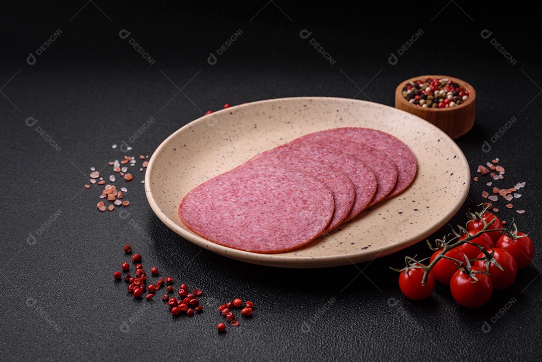 Deliciosa salsicha de salame fumado com sal, especiarias e ervas cortadas em fatias sobre um fundo escuro de concreto
