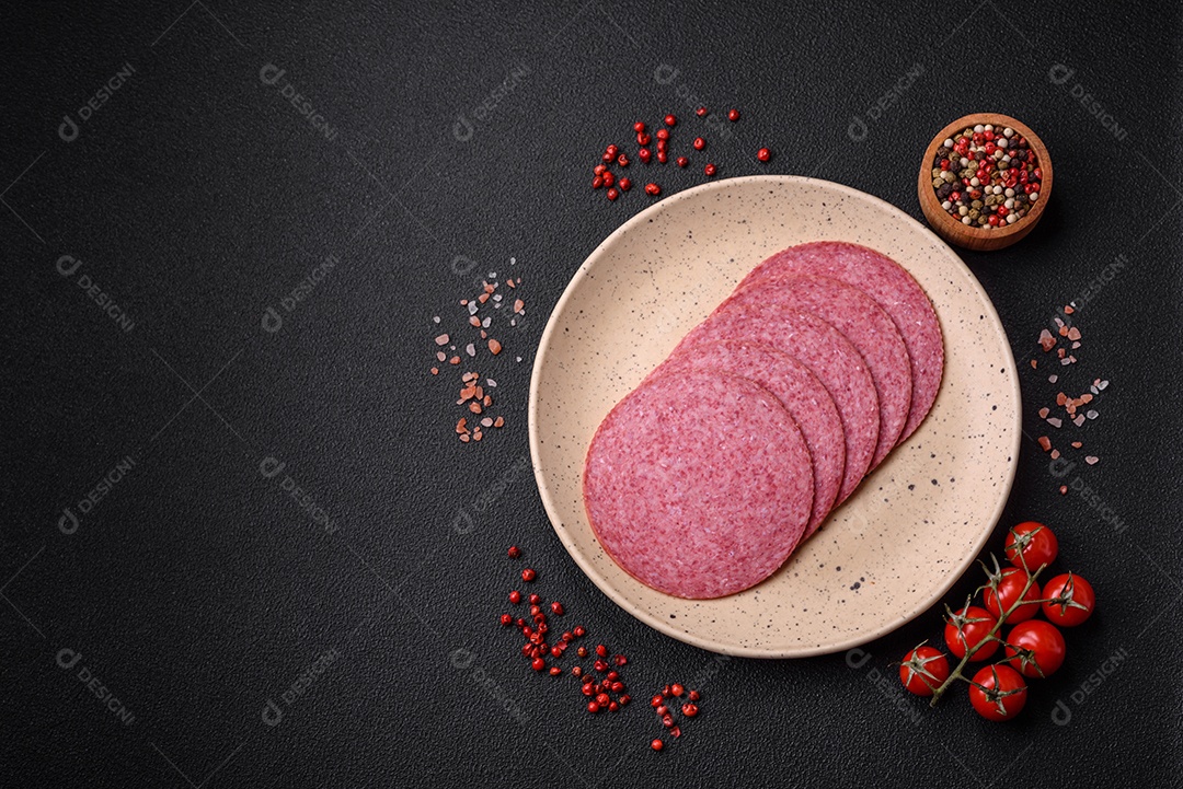 Deliciosa salsicha de salame fumado com sal, especiarias e ervas cortadas em fatias sobre um fundo escuro de concreto