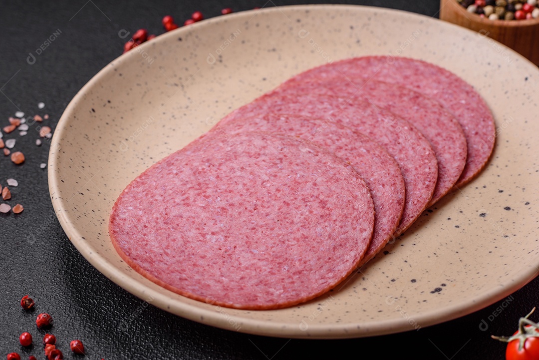 Deliciosa salsicha de salame fumado com sal, especiarias e ervas cortadas em fatias sobre um fundo escuro de concreto
