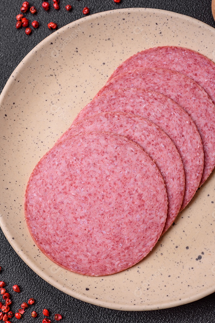 Deliciosa salsicha de salame fumado com sal, especiarias e ervas cortadas em fatias sobre um fundo escuro de concreto