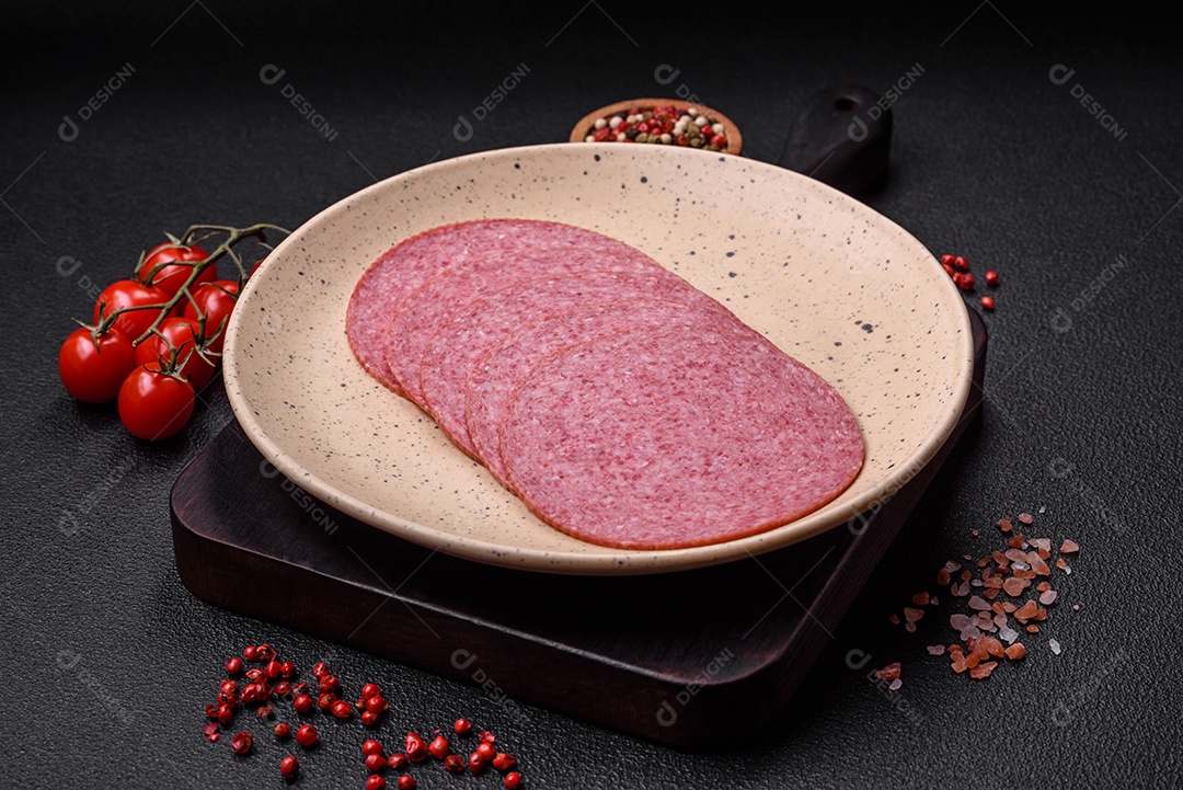 Deliciosa salsicha de salame fumado com sal, especiarias e ervas cortadas em fatias sobre um fundo escuro de concreto