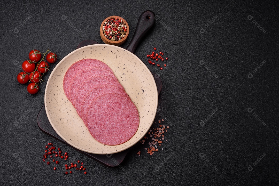 Deliciosa salsicha de salame fumado com sal, especiarias e ervas cortadas em fatias sobre um fundo escuro de concreto