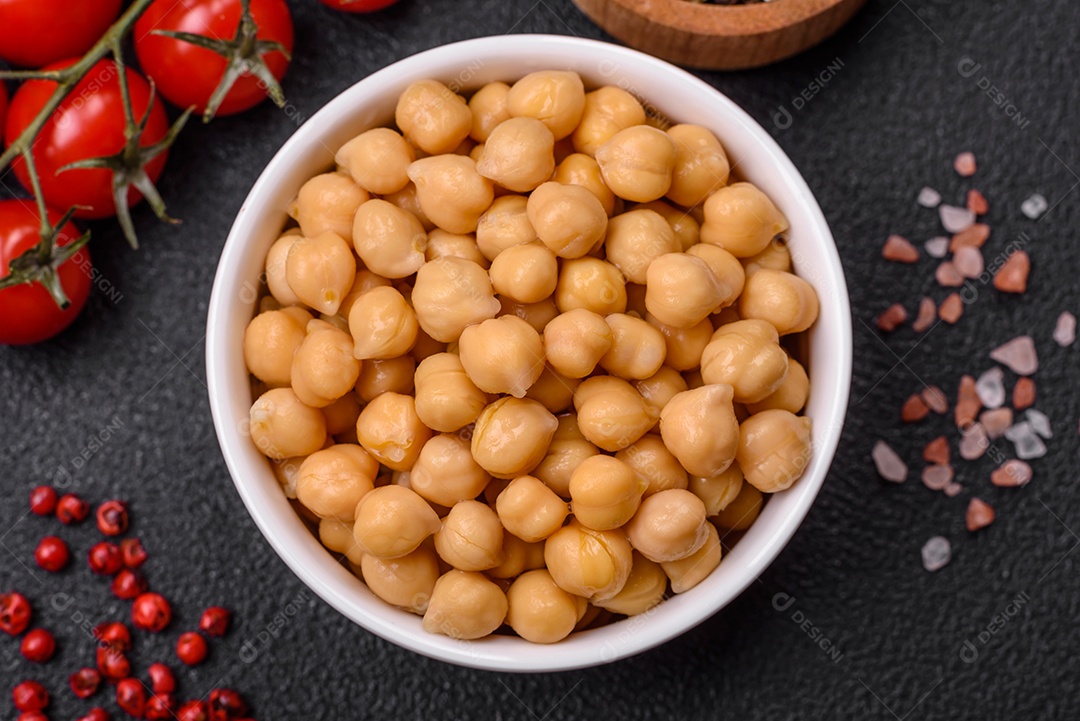 Delicioso grão de bico enlatado em um prato de cerâmica sobre um fundo escuro de concreto. Ingrediente para pratos vegetarianos