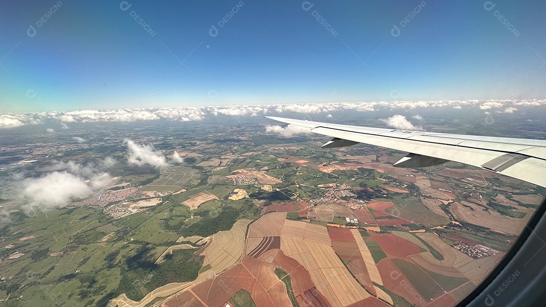 Foto da paisagem verde brasileira e do céu nublado tirada de avião