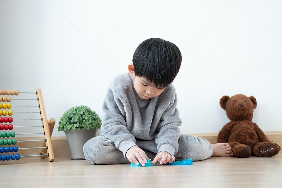 Menino asiático lindo brincando de amoeba na sala