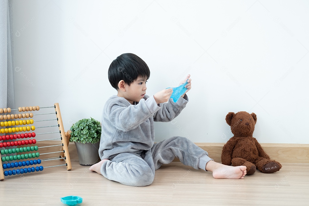 Menino lindo asiático brincando com e slime na sala