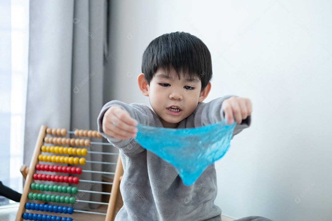 Menino lindo asiático brincando com e slime na sala