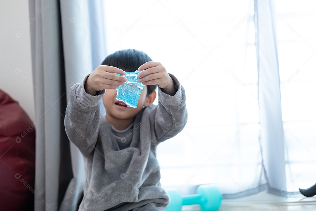 Menino lindo asiático brincando com e slime na sala